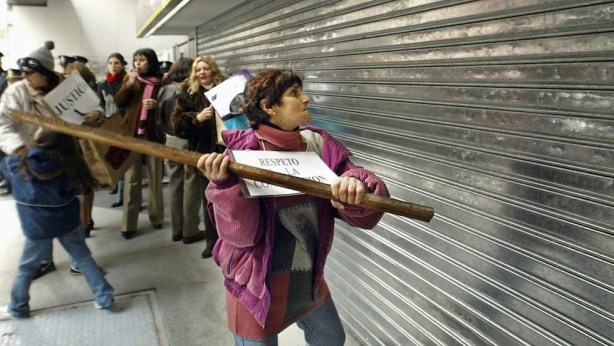 A protester strikes the blind of the Galicia Bank